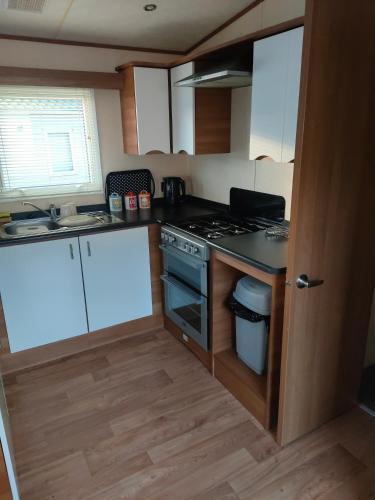 凯恩莱安Cairnryan Heights t-a Brae Holiday Homes的小厨房配有白色橱柜和炉灶。