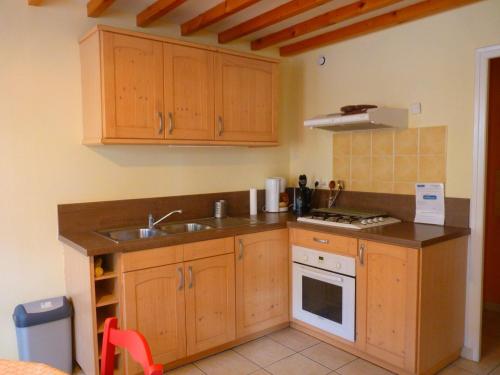 Bény-sur-Mer全面翻修5人老屋的厨房配有木制橱柜、水槽和炉灶。