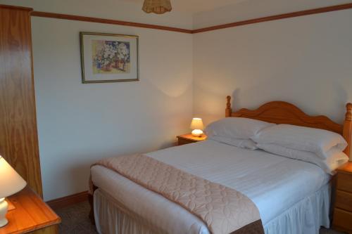 StokeinteignheadPalm Tree Cottage的卧室配有一张带白色床单的床,墙上挂着一幅画