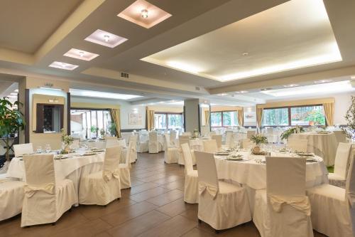 塔瓦娜Parco dei Pini - Sila Wellness Hotel的宴会厅配有白色的桌椅