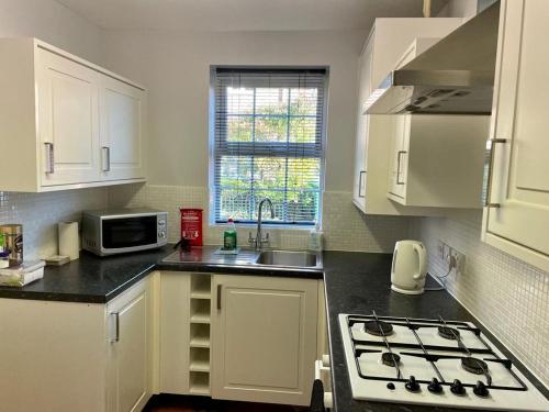 哈勒斯登Bullfinch House的厨房配有白色橱柜、水槽和微波炉
