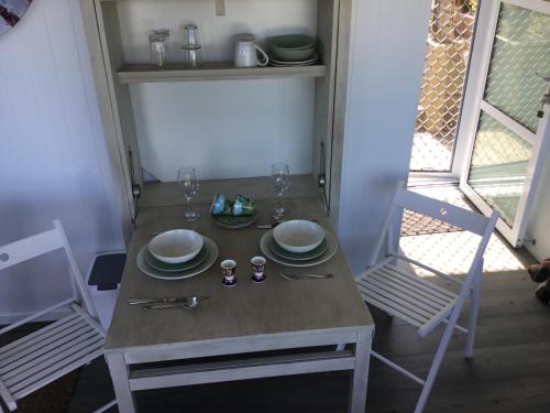 陶朗加Sunset Cottage的一张桌子,上面有盘子和玻璃杯,上面有两把椅子