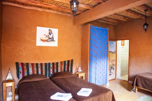 Aït BoukhaLa Maison de l'Homme Bleu的一间卧室设有两张床,墙上挂着一幅画