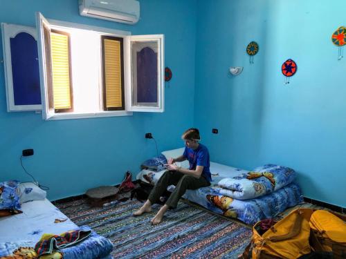 阿斯旺Nubian Kingdom Aragheed House的坐在蓝色房间床上的男孩