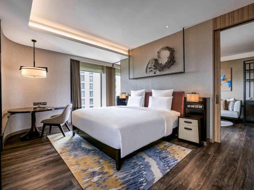 万隆Pullman Bandung Grand Central的酒店客房设有一张白色大床和一张书桌