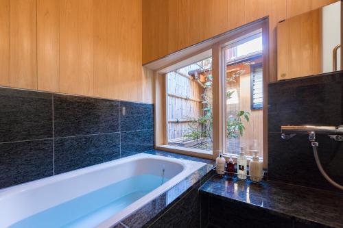 京都京町家套房利休的带浴缸的浴室和窗户。