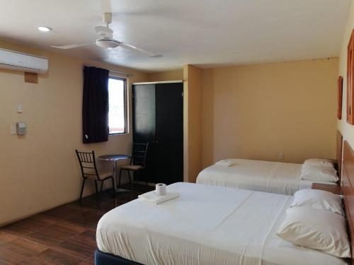 坎佩切Hotel Bugambilia Campeche的酒店客房带两张床和一张桌子以及椅子。