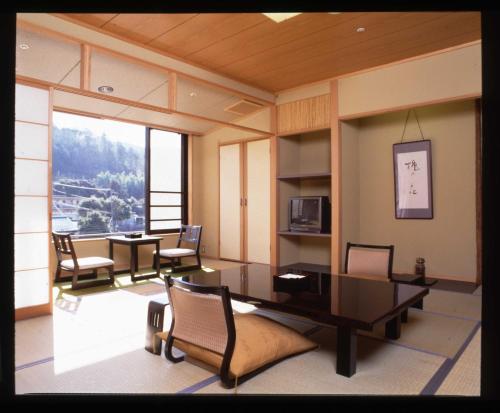 伊豆丸久旅馆的客房设有桌椅和大窗户。