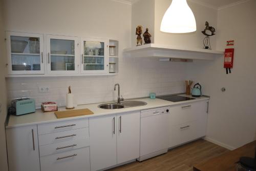 古勒冈Casa do Tio Zé的厨房配有白色橱柜、水槽和灯