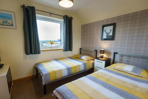 洛西茅斯Lossiemouth Haven的一间卧室设有两张床和窗户。