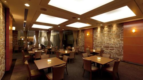 东京Hotel Grand Hill Ichigaya的一间带桌椅和石墙的餐厅