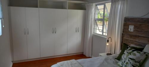 东伦敦StayMore的卧室配有白色橱柜、床和窗户。