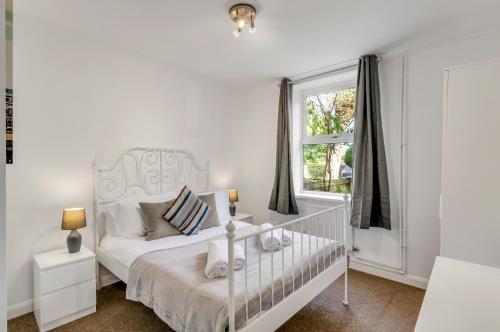EarlhamGuest Homes - The Lodge的白色卧室设有婴儿床和窗户