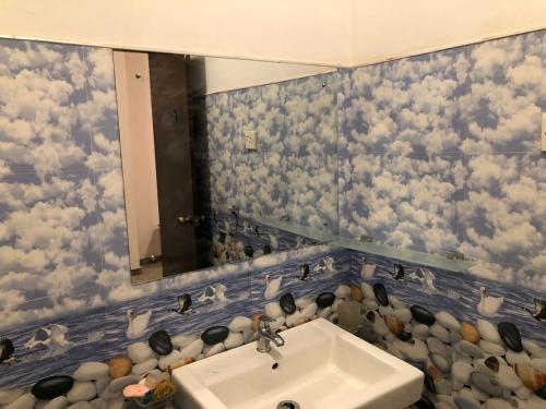 康提安尼瓦特豪斯酒店的浴室设有水槽,墙上有一面镜子,上面有云彩