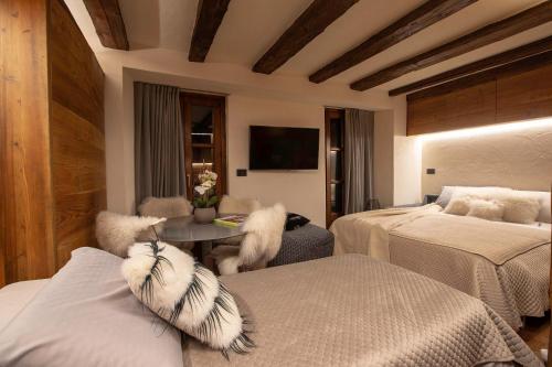 库马约尔L.A. SUITE Courmayeur的一间卧室配有两张床和一张带毛绒枕头的桌子。