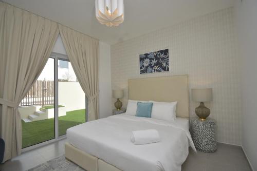 迪拜bnbmehomes - Elegant 3 BR - Dubai South - G04的卧室设有白色的床和大窗户