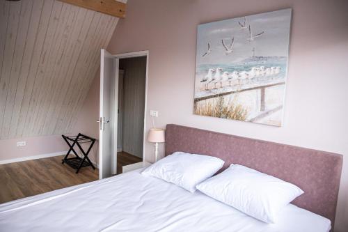 德科赫Het Mienterbos的卧室配有一张床,墙上挂有绘画作品
