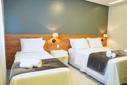 皮拉尼亚斯Pousada Encanto dos Canyons的配有白色床单的酒店客房内的两张床