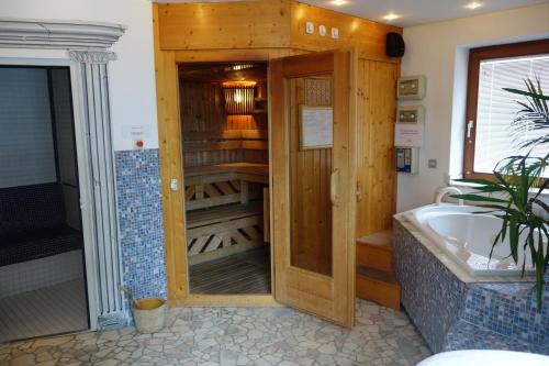 KrakaudorfEdelsteinhotel Guniwirt的带浴缸的浴室和木制衣柜。