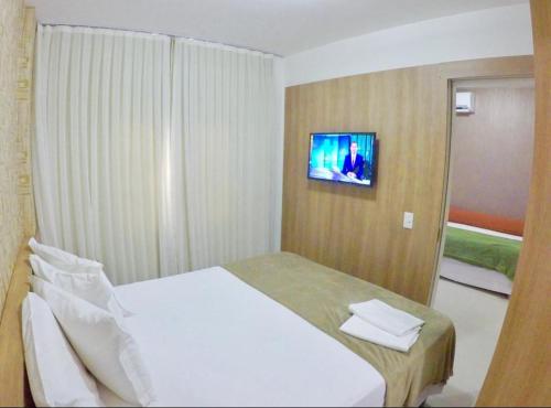 福塔莱萨VG FUN-OCEAN VIEW BEACH FRONT APARTMENT-Fortaleza的卧室配有白色的床和墙上的电视。