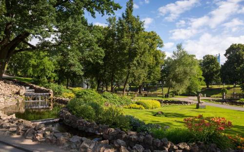 里加Radisson Hotel Old Town Riga的公园里有一个池塘,花树