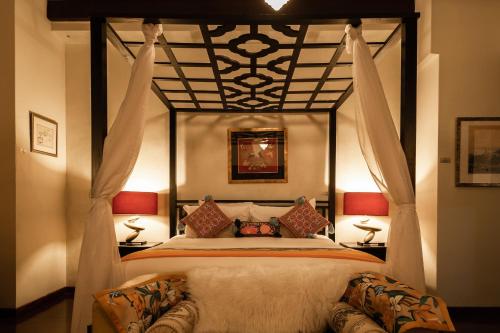 乔治市柏那卡精品酒店的一间卧室配有一张天蓬床和两盏灯。