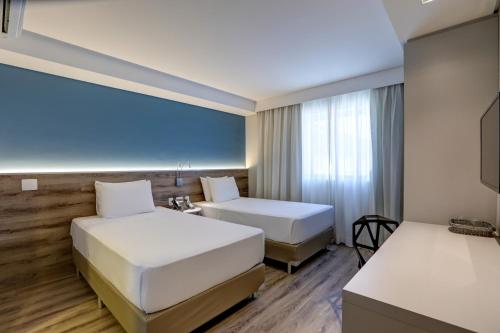 瓜鲁柳斯Comfort Hotel Guarulhos Aeroporto的酒店客房设有两张床和窗户。