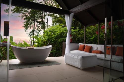 乌维塔Oxygen Jungle Villas & Spa的浴缸位于带沙发的庭院