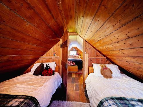 PortobelloPortobello Settler's Cottage的木制客房内的一间卧室配有两张床