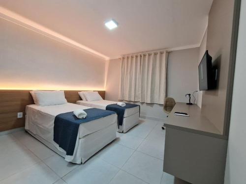 巴纳伊巴Hotel Aveiro的酒店客房配有两张床和一张书桌
