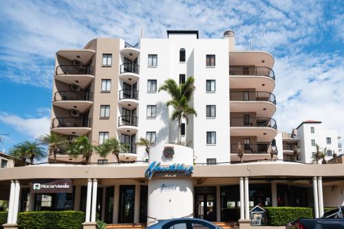 穆卢拉巴鹦鹉螺穆鲁拉巴度假酒店的一座白色的建筑,前面有棕榈树