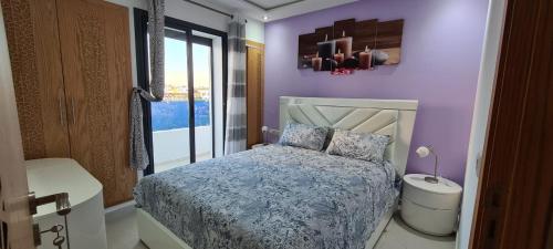 盖尼特拉SuperAppart KENITRA的卧室设有紫色墙壁、床和窗户
