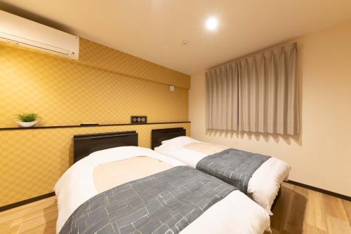 箱根スタジオーネ 箱根強羅 East - Stagione Hakone Gora East的黄色墙壁客房的两张床