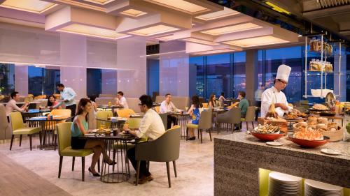 新加坡JEN Singapore Orchardgateway by Shangri-La的餐厅有坐在桌子旁的人,厨师准备食物