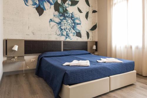 马尼亚戈Albergo Leon D'Oro的一间卧室配有蓝色的床和毛巾