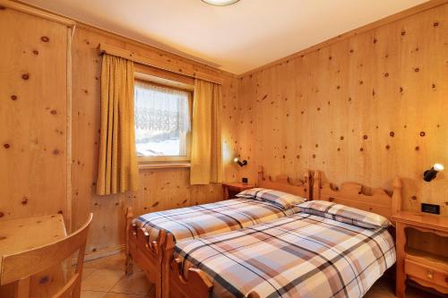 利维尼奥Baita sulle Alpi的卧室配有一张床铺,位于带木墙的房间内
