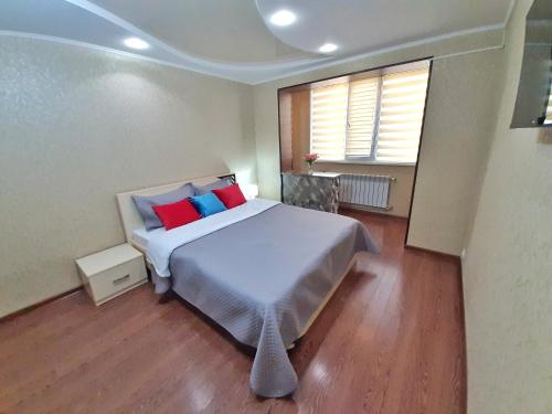 塔拉兹Уютная квартира класса ЛЮКС в городе Тараз的一间卧室配有一张带红色和蓝色枕头的大床