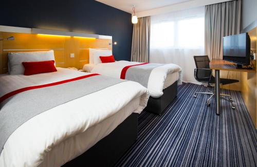 埃普瑟姆伦敦智选假日酒店 - 埃普森姆当斯的酒店客房设有两张床、一张桌子和一台电视。