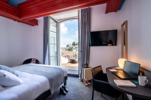 洛什Best Western Premier Hotel de la Cite Royale的酒店客房配有一张床、一张书桌和一台笔记本电脑