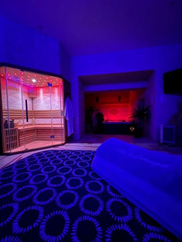 圣耐克森Suite Privative Jacuzzi Sauna de la Villa Del Castagnol的一间卧室配有一张床,另一间房间配有紫色灯