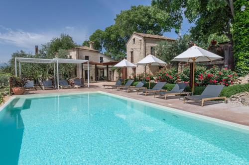 CrecchioBorgo Baccile by Vini Fantini的房屋旁的游泳池配有椅子和遮阳伞