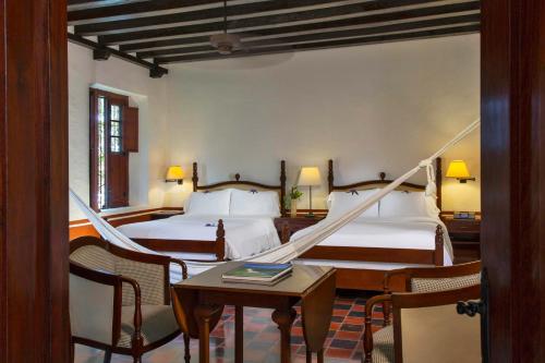 坎佩切Hacienda Campeche的一间卧室配有两张床和一张桌子及椅子