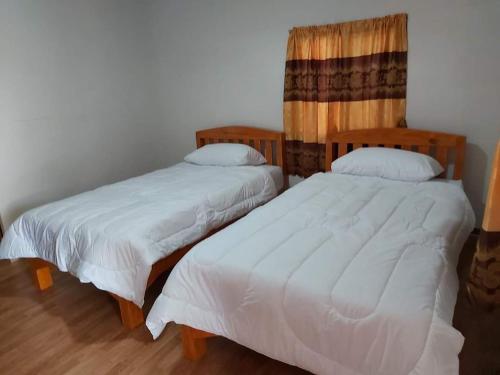 Ban Pa Tiuริมทุ่งโฮมสเตย์的配有2张床的带白色毯子和枕头的客房