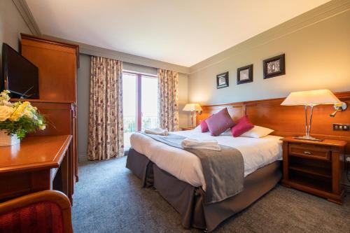 布莱克伍德布莱恩牧场高尔夫球、酒店&SPA的酒店客房设有一张大床和一张书桌。