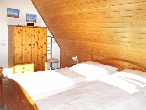 多鲁姆纽菲尔德Holiday Home Cuxland Ferienpark-1 by Interhome的一间卧室设有一张带木墙的大床