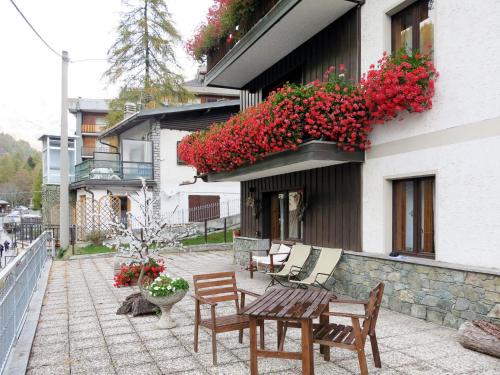 瓦托内切Apartment La Tata by Interhome的庭院配有桌椅和红色鲜花。