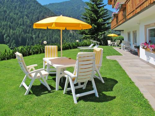 圣克里斯蒂娜Apartment Ornella-1 by Interhome的草坪上配有桌椅和雨伞