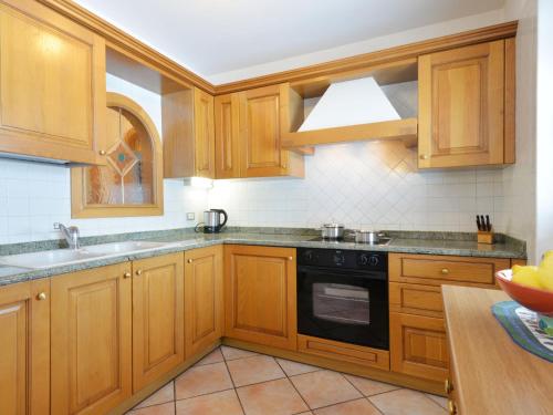 坎皮泰洛Apartment Ardoney-1 by Interhome的厨房配有木制橱柜和黑炉灶烤箱。