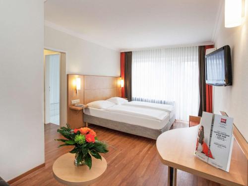 萨尔布吕肯萨尔布吕肯宜必思酒店的配有床和鲜花桌的酒店客房