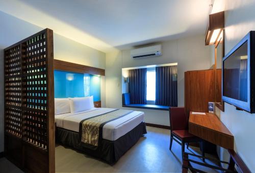 马尼拉Microtel by Wyndham UP Technohub的酒店客房,配有床和电视